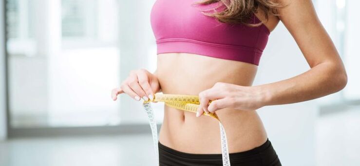 Das Mädchen misst die Taille mit einem Zentimeter